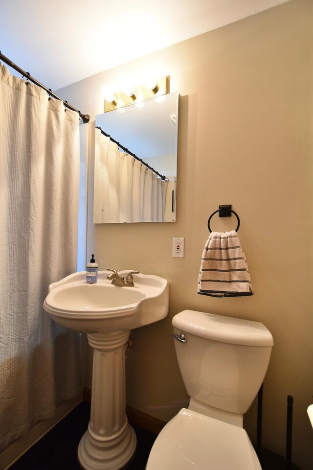 bathroom featuring curtained shower and toilet