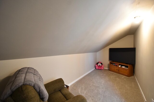living area featuring light colored carpet, vaulted ceiling, and baseboards