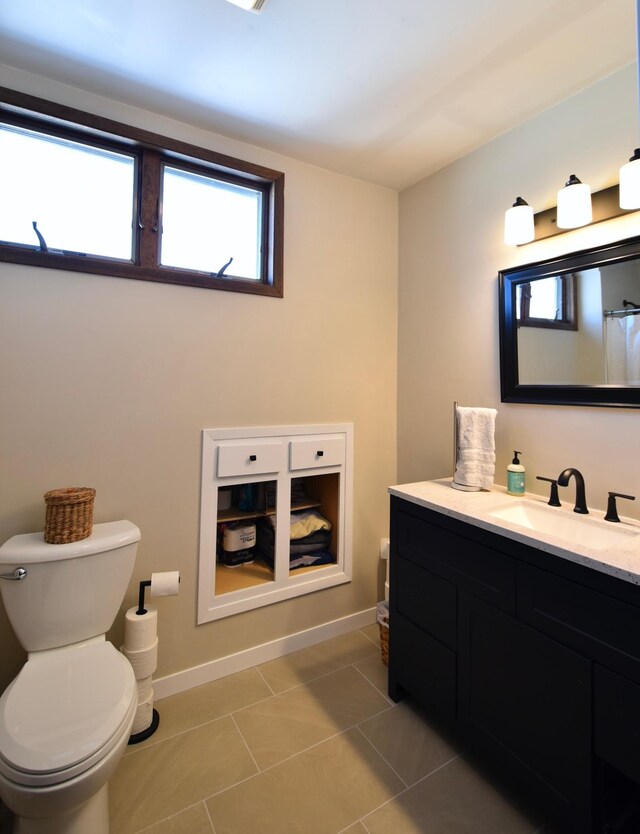 bathroom with tile patterned flooring, toilet, vanity, and baseboards