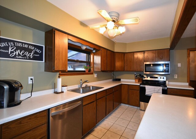 kitchen featuring stainless steel appliances, a sink, a ceiling fan, light countertops, and light tile patterned floors