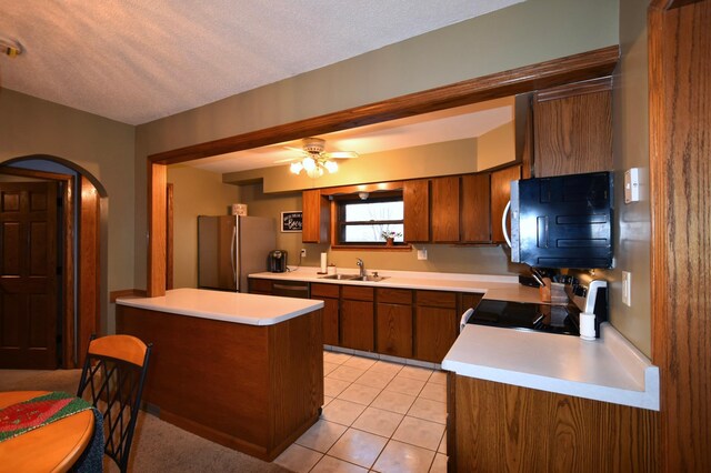 kitchen with a sink, freestanding refrigerator, brown cabinets, range with electric stovetop, and light countertops