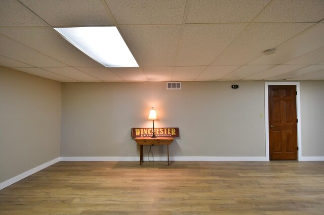 unfurnished room featuring wood finished floors, baseboards, a paneled ceiling, and visible vents