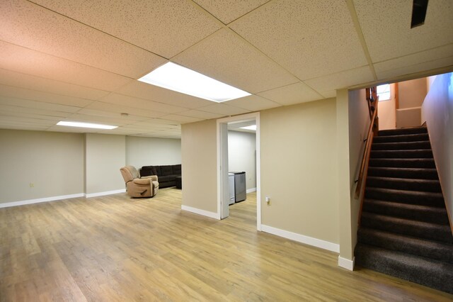 finished below grade area with stairway, baseboards, wood finished floors, and a drop ceiling