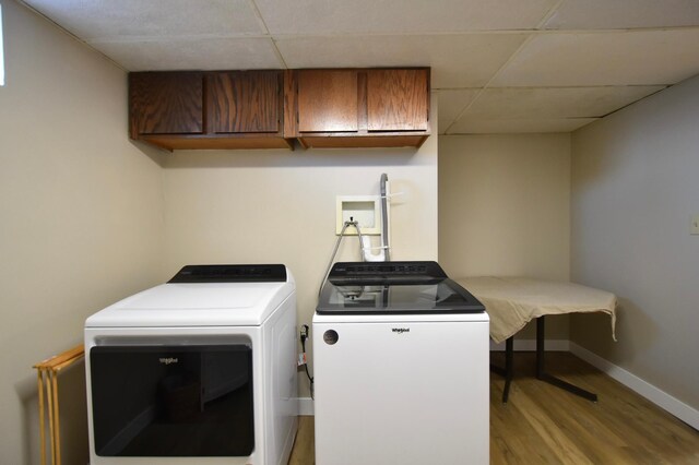 laundry area featuring separate washer and dryer, baseboards, wood finished floors, and cabinet space
