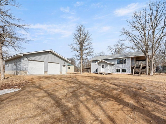 view of front of home with a detached garage, an outbuilding, and stairs