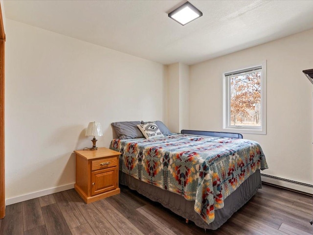 bedroom featuring dark wood-type flooring, baseboards, and a baseboard heating unit