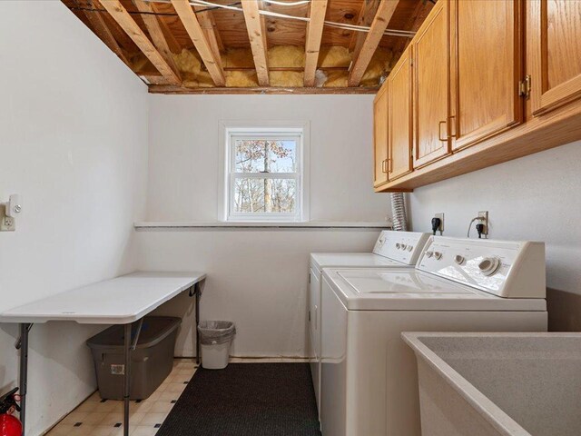 washroom with cabinet space, a sink, light floors, and washer and clothes dryer