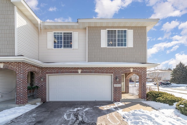 multi unit property featuring driveway, a garage, and brick siding