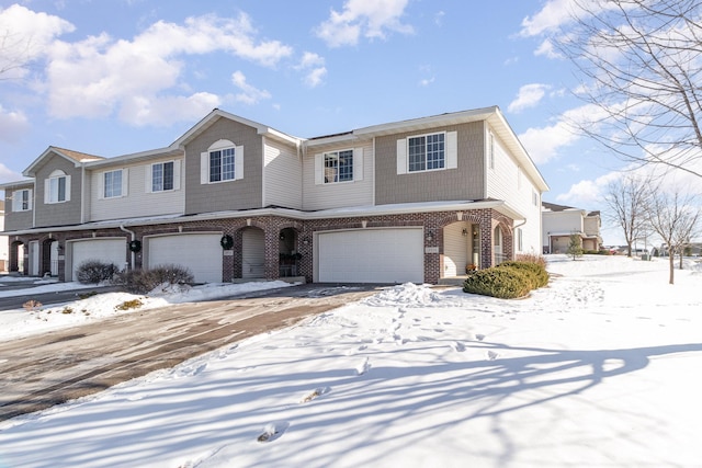 multi unit property with an attached garage and brick siding