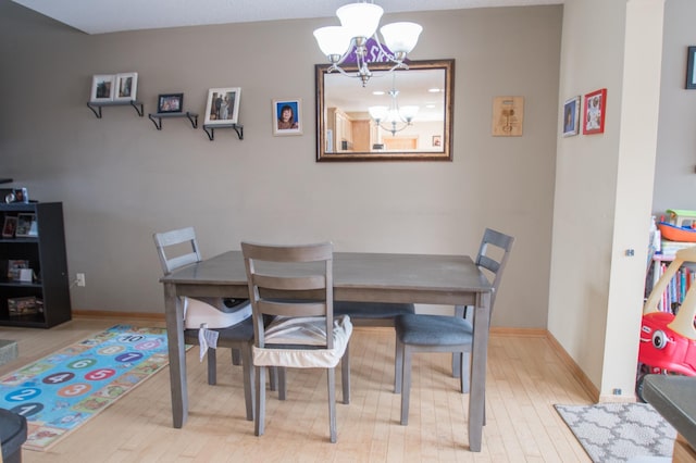 dining area featuring wood finished floors, baseboards, and an inviting chandelier