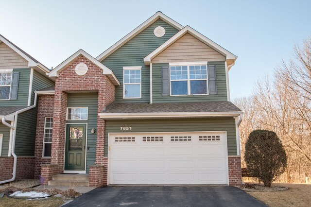 view of front of property with aphalt driveway, a garage, roof with shingles, and brick siding