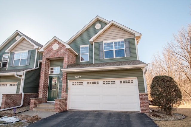 view of front of house with aphalt driveway, an attached garage, a shingled roof, and brick siding