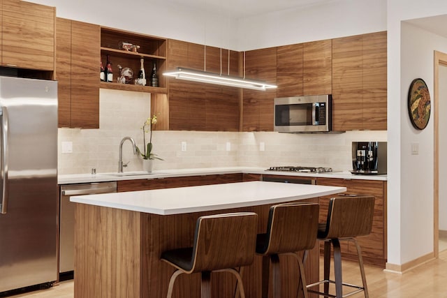 kitchen featuring backsplash, brown cabinets, stainless steel appliances, and light countertops