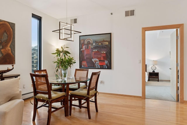 dining space with visible vents, a baseboard heating unit, light wood-type flooring, and baseboards