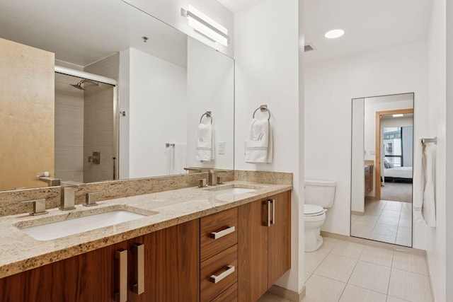 ensuite bathroom featuring tile patterned flooring, a shower stall, toilet, and a sink