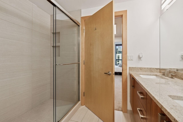 bathroom featuring tile patterned floors, ensuite bathroom, a sink, a shower stall, and double vanity