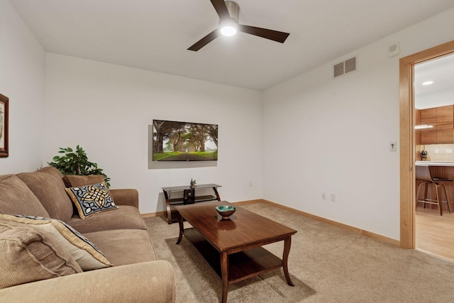 living room featuring visible vents, baseboards, light colored carpet, and ceiling fan