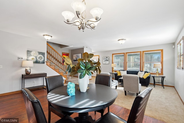 dining room featuring baseboards, stairway, wood finished floors, and an inviting chandelier