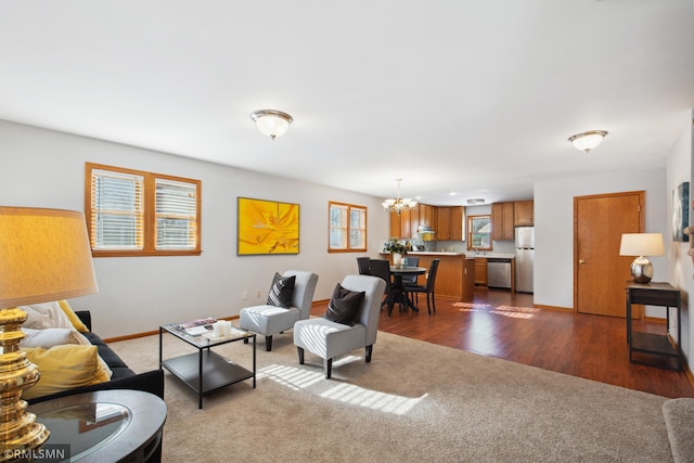 living area featuring dark carpet, baseboards, a chandelier, and dark wood finished floors