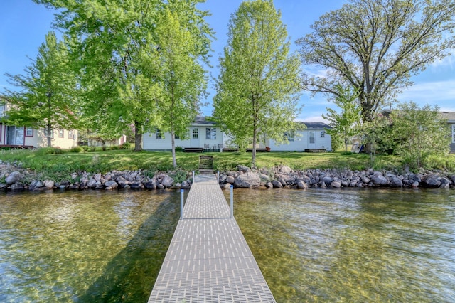 view of dock with a lawn and a water view