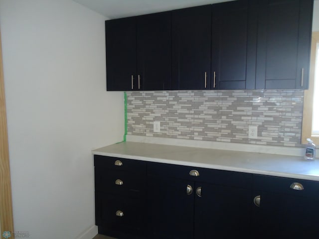 212 May Ave, Page, ND 58064 - kitchen featuring light countertops, dark cabinetry, decorative backsplash, and baseboards