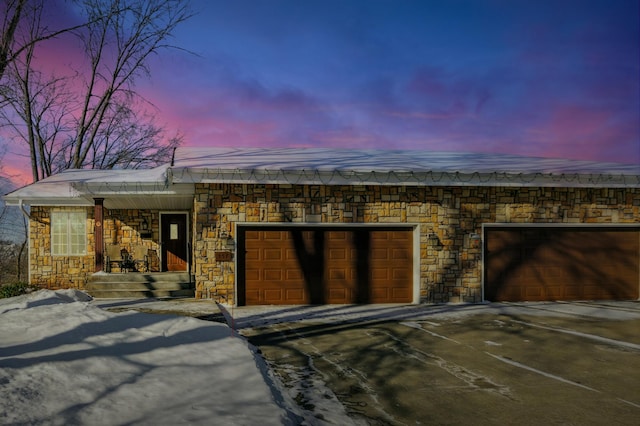 view of front of property featuring driveway, stone siding, and an attached garage