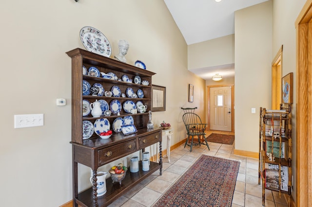 entryway with high vaulted ceiling, light tile patterned flooring, and baseboards