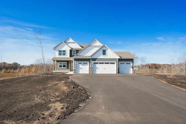 view of front of home with board and batten siding, concrete driveway, an attached garage, and stone siding