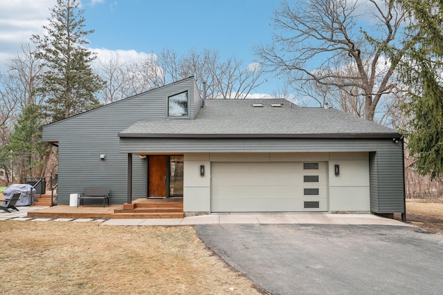 view of front facade with driveway, a shingled roof, and an attached garage