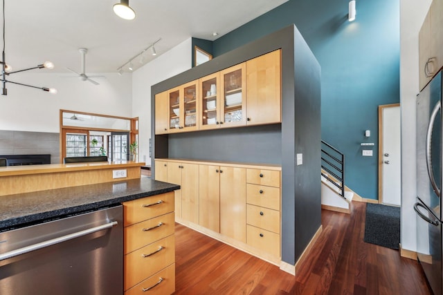 kitchen featuring dark wood-style floors, glass insert cabinets, appliances with stainless steel finishes, rail lighting, and light brown cabinetry