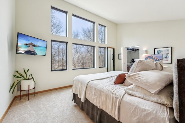 bedroom with a high ceiling, carpet flooring, and baseboards