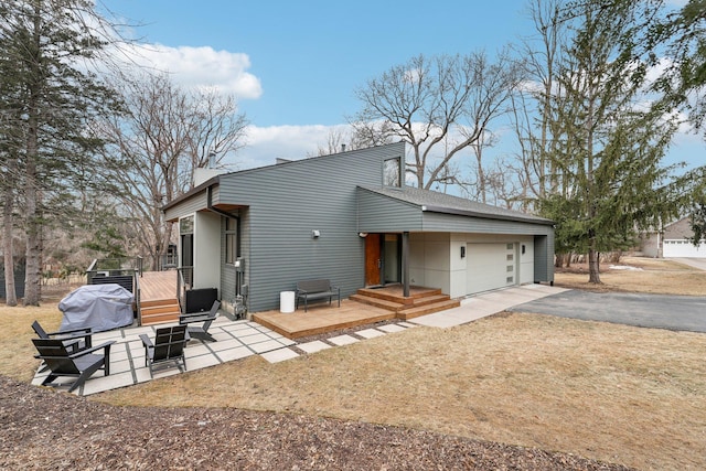 exterior space featuring aphalt driveway, a patio, and an attached garage