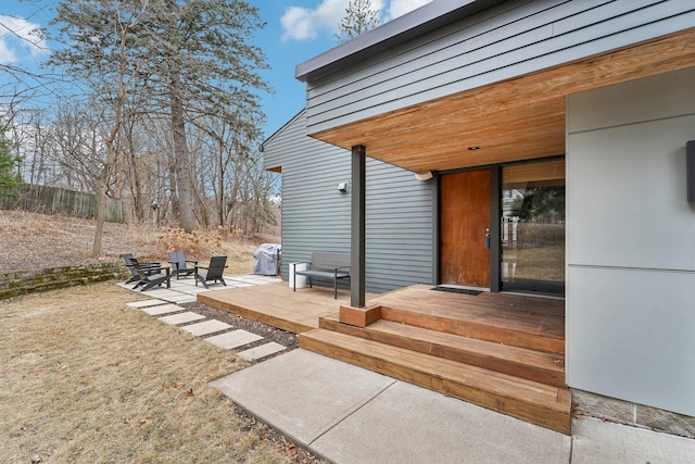 view of exterior entry with a patio area and fence