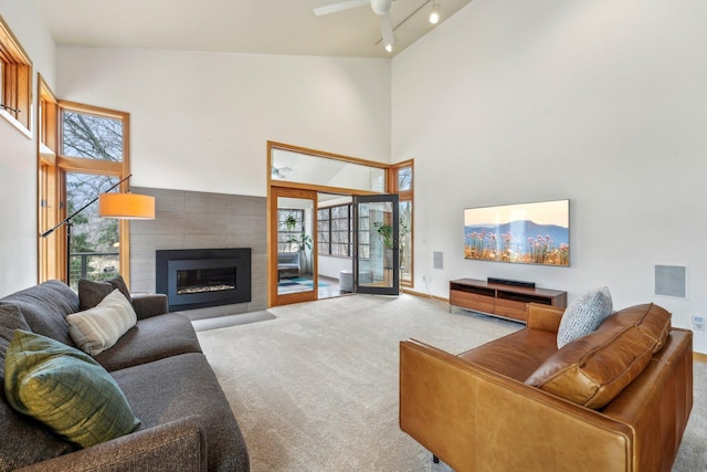 living area featuring carpet floors, a fireplace, rail lighting, and a towering ceiling