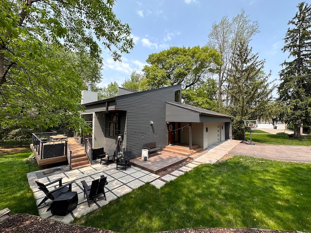 rear view of property featuring a deck, a yard, a patio area, and driveway