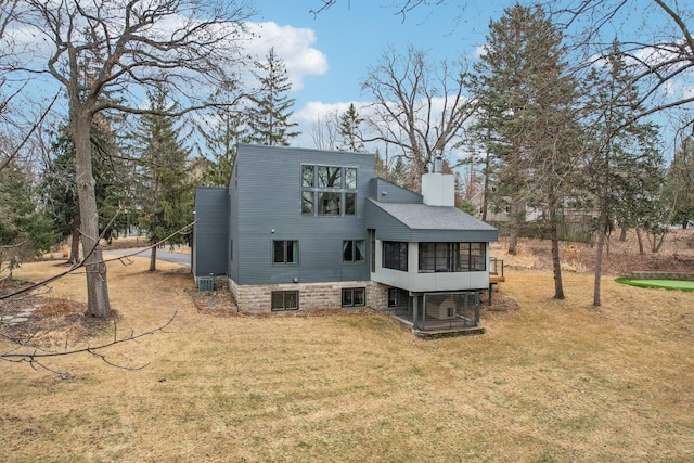 back of house featuring central air condition unit, a shingled roof, a chimney, and a yard