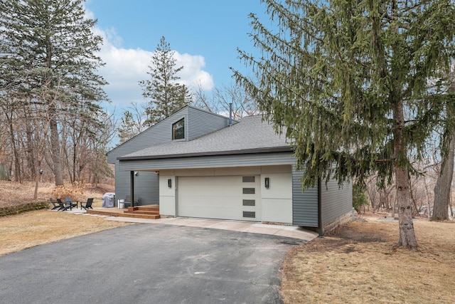 view of front of property with aphalt driveway, a shingled roof, and an attached garage