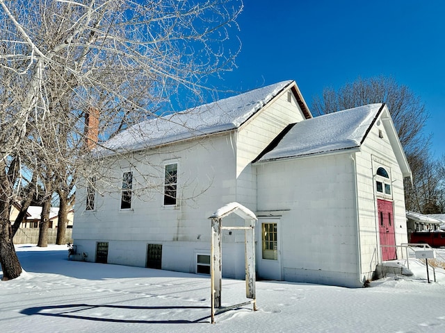 snow covered property featuring concrete block siding and a chimney