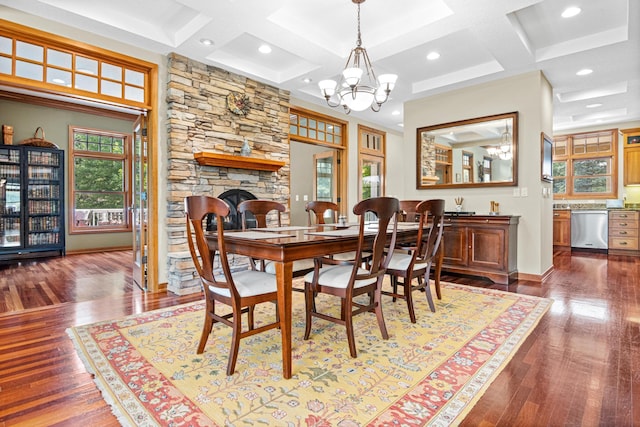 dining room featuring coffered ceiling, a fireplace, an inviting chandelier, and wood finished floors