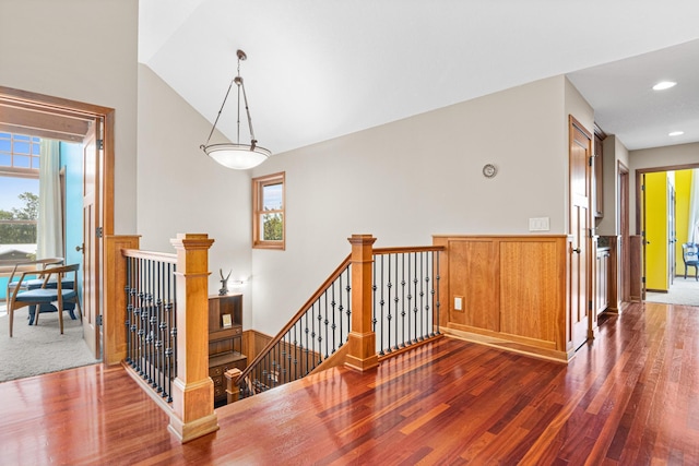 hallway with plenty of natural light, vaulted ceiling, dark wood-style flooring, and an upstairs landing