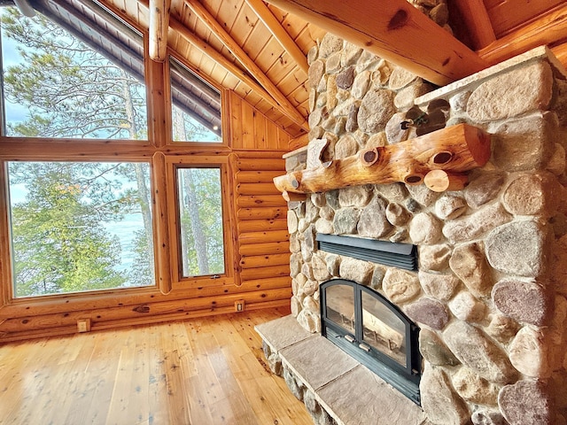 unfurnished living room with log walls, wood-type flooring, a stone fireplace, and wooden ceiling
