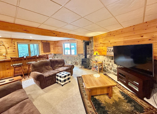 living area with wooden walls, carpet, a wood stove, and a bar