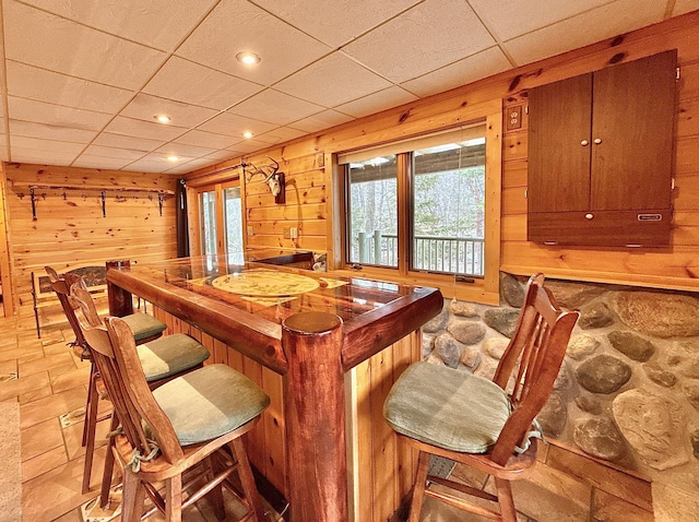 indoor bar featuring wood walls, light stone finish floors, and recessed lighting