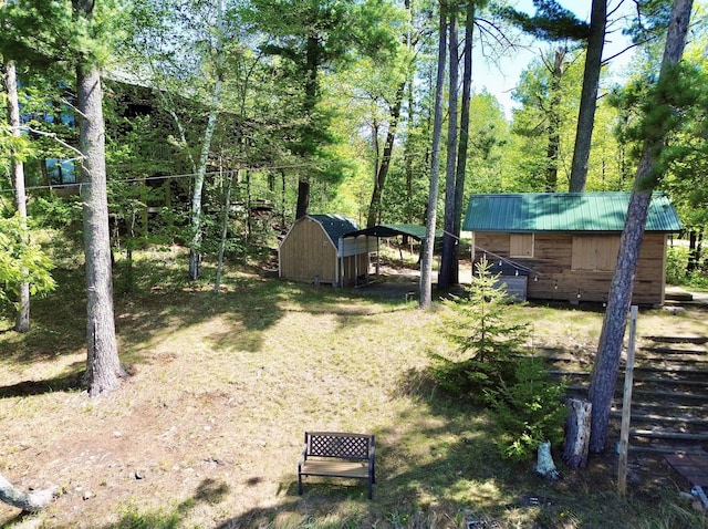 view of yard featuring a storage unit, a carport, and an outdoor structure
