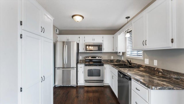 kitchen featuring stainless steel appliances, dark wood finished floors, a sink, and white cabinetry