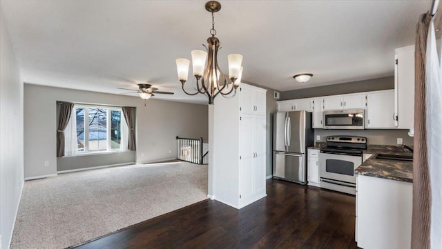 kitchen featuring white cabinets, dark countertops, decorative light fixtures, stainless steel appliances, and a sink