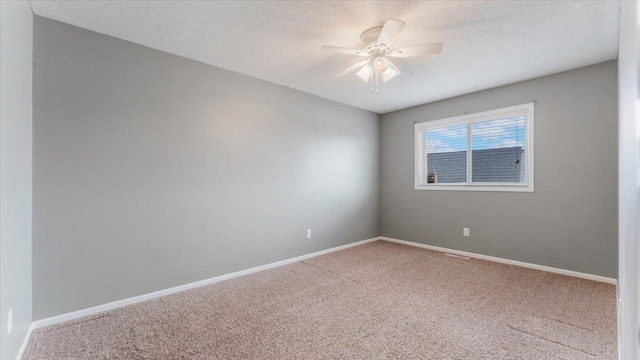 carpeted empty room featuring ceiling fan, a textured ceiling, and baseboards