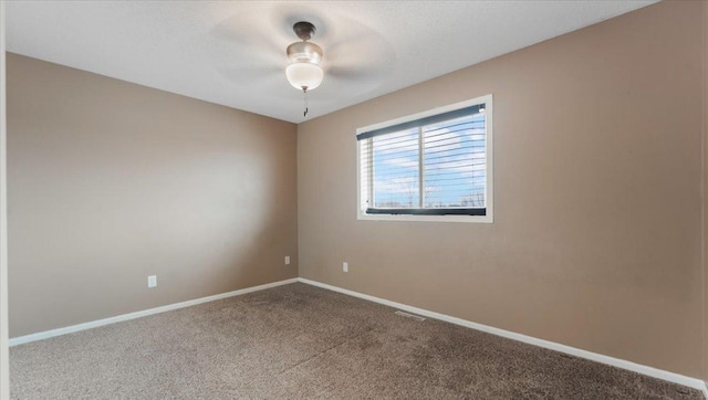 carpeted spare room with a ceiling fan and baseboards