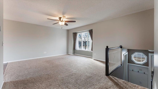 unfurnished room featuring a textured ceiling, carpet flooring, a ceiling fan, and baseboards