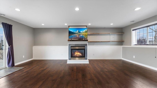 unfurnished living room featuring recessed lighting, wood finished floors, and a glass covered fireplace